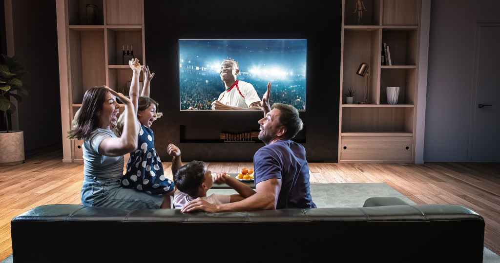 A family cheering while watching sports TV at home