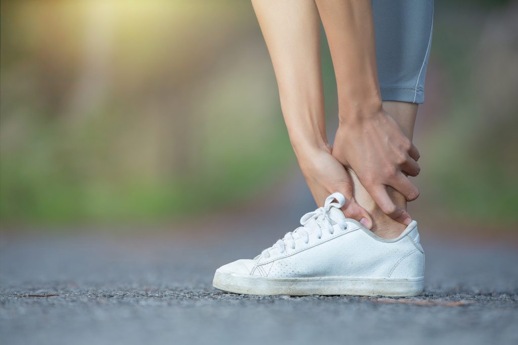close-up of a foot in a running shoe with hands clasped around the ankle