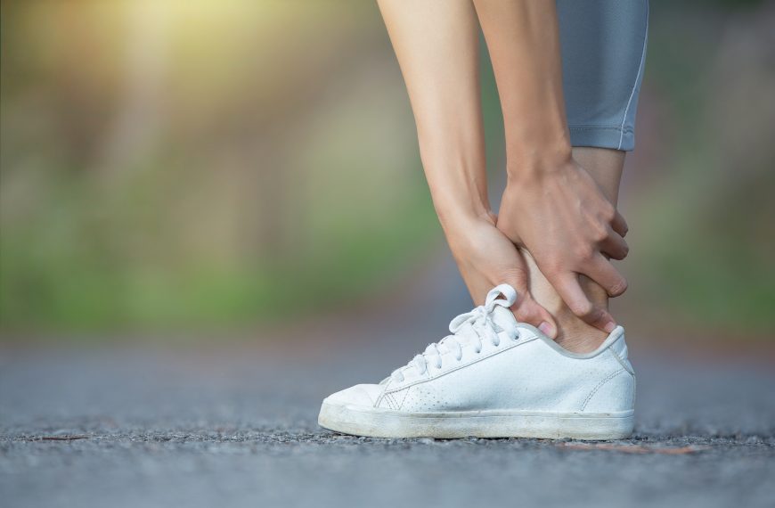 close-up of a foot in a running shoe with hands clasped around the ankle